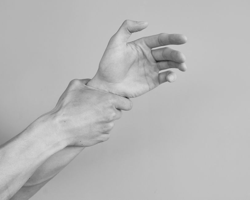 Grayscale image of hands gripping a wrist, symbolizing tension or support.