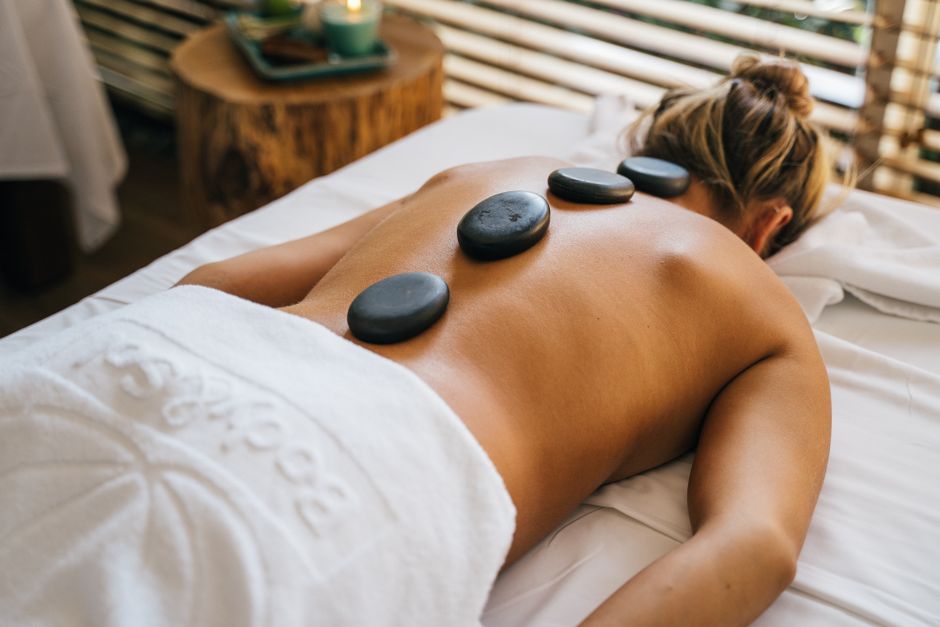 Woman enjoying a soothing hot stone massage on her back in a serene spa setting.